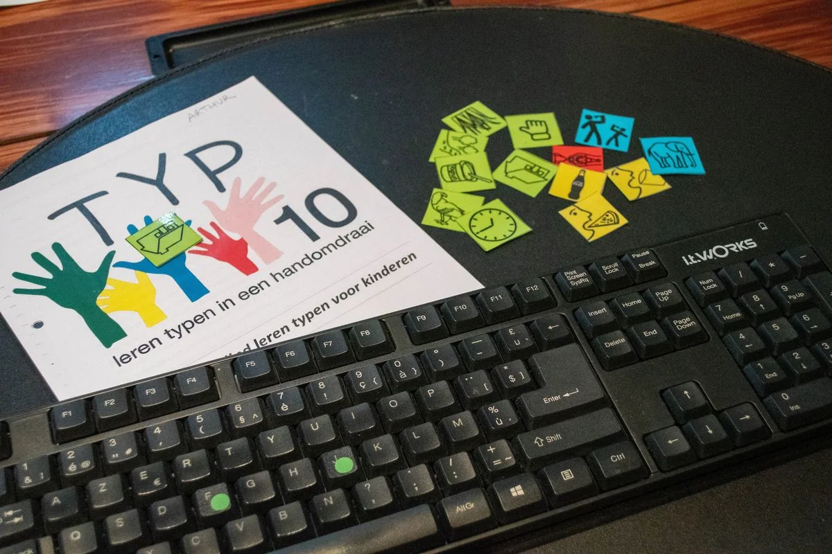 Typtien-oefenboek naast een toetsenbord: blind leren typen met tien vingers